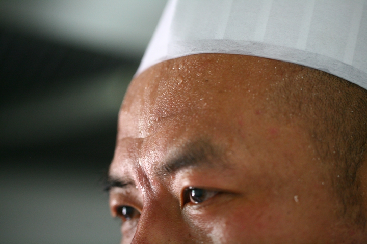 高温加上炉火炙烤,厨师汗滴如雨.